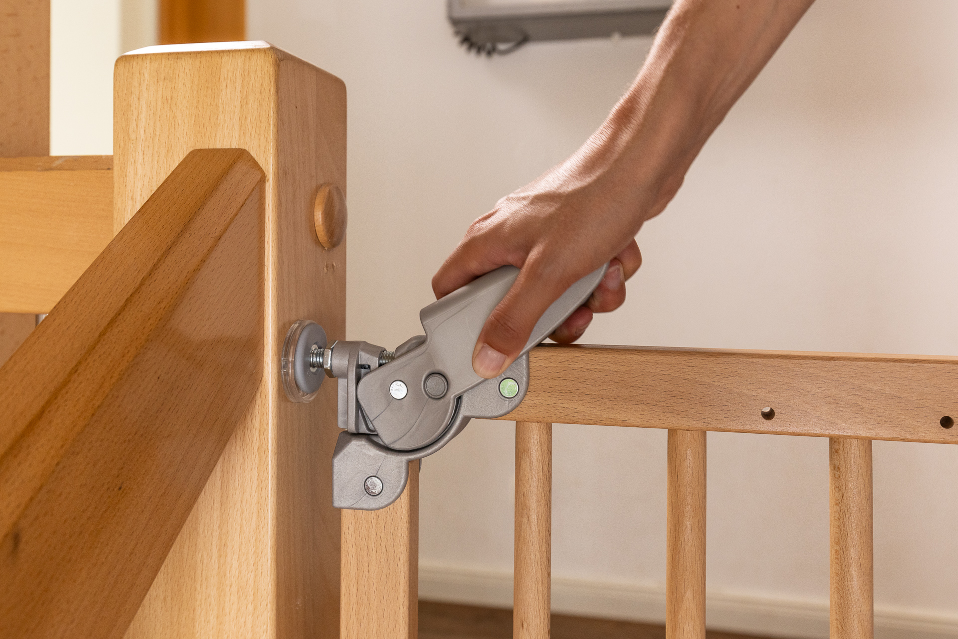 Mano accionando el cierre de seguridad de una barrera de madera SOGEM, mostrando un sistema de apertura práctico con una sola mano, fijado de forma segura a un poste de escalera.
