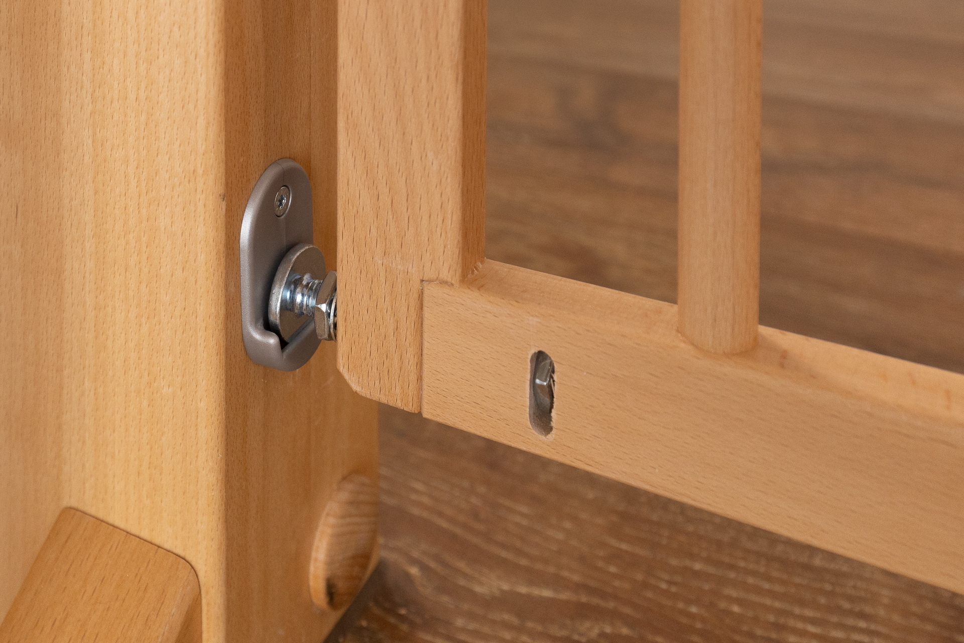 Primer plano del sistema de fijación atornillado de una barrera de seguridad de madera, firmemente sujeta a una pared con acabado metálico.