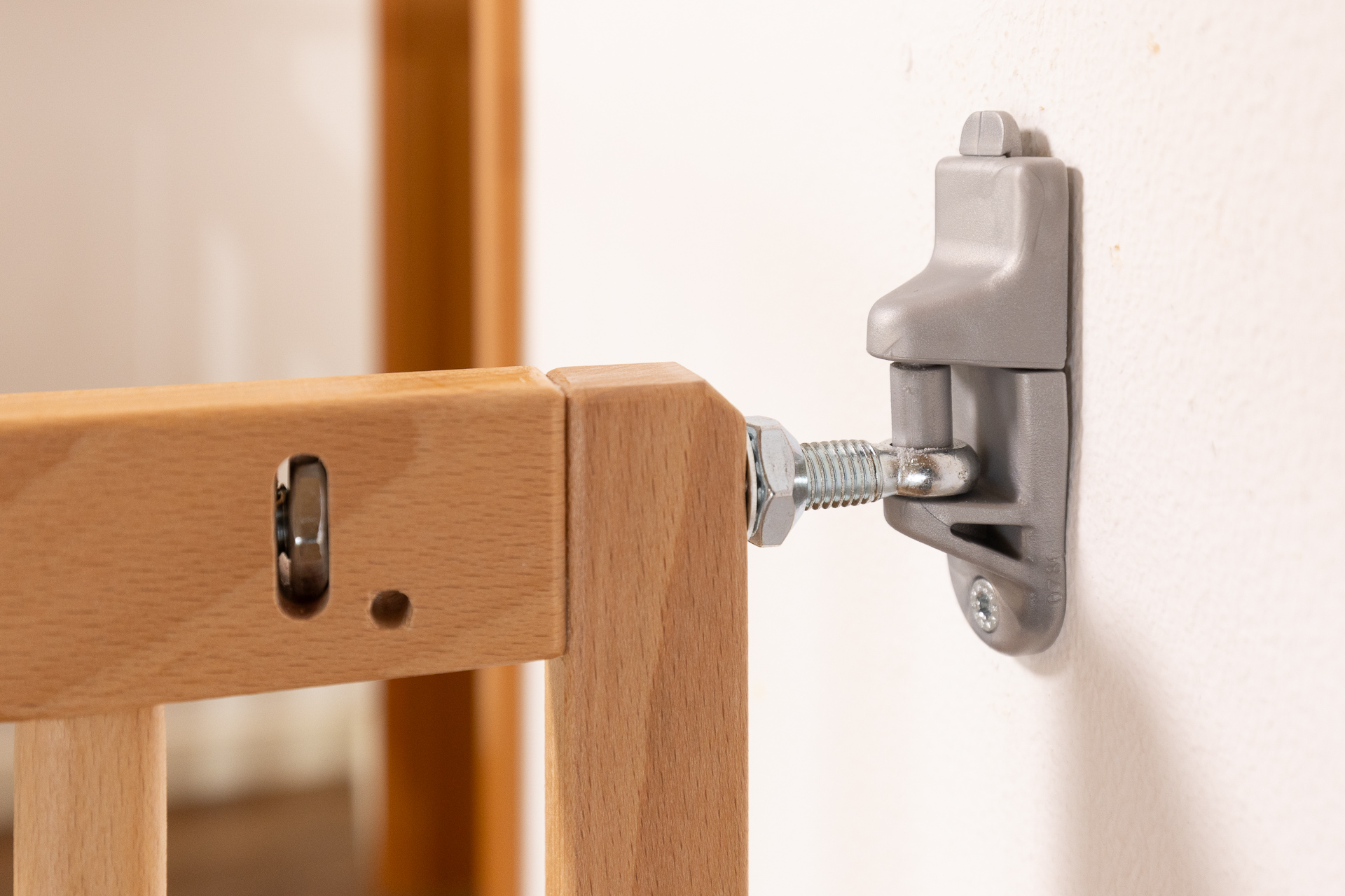 Sistema de fijación metálico de una barrera de seguridad de madera SOGEM, atornillado de forma segura a una pared, con tornillo de ajuste visible.